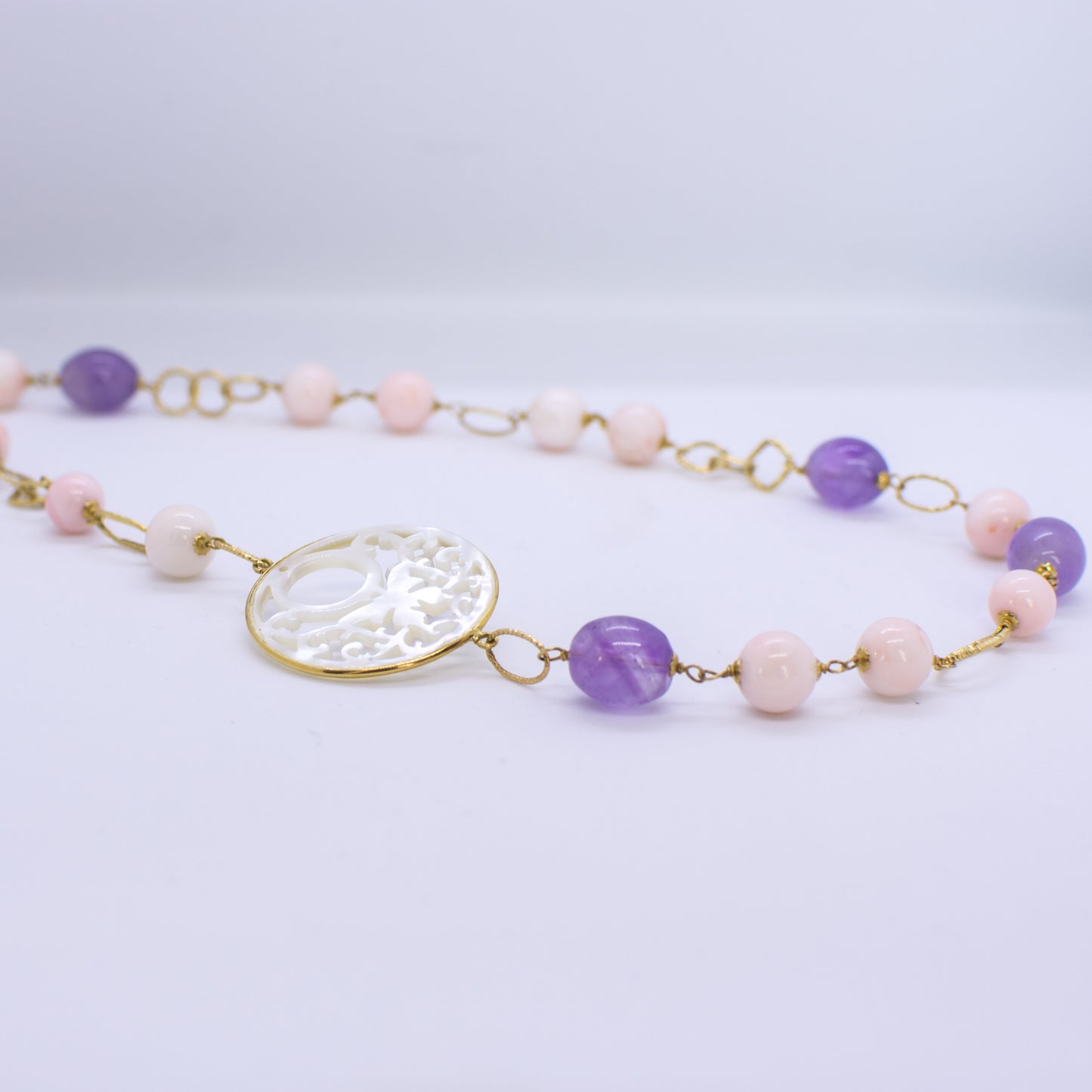 18ct Gold Mother of Pearl fancy cut out, Rose Coral bead and Silky Amethyst Necklace Asymmetrical pattern with the Mother of Pearl cut out positioned on the collarbone.  This necklace is hand made an features fancy round, oval and square links. 52cm necklace 18ct yellow gold
