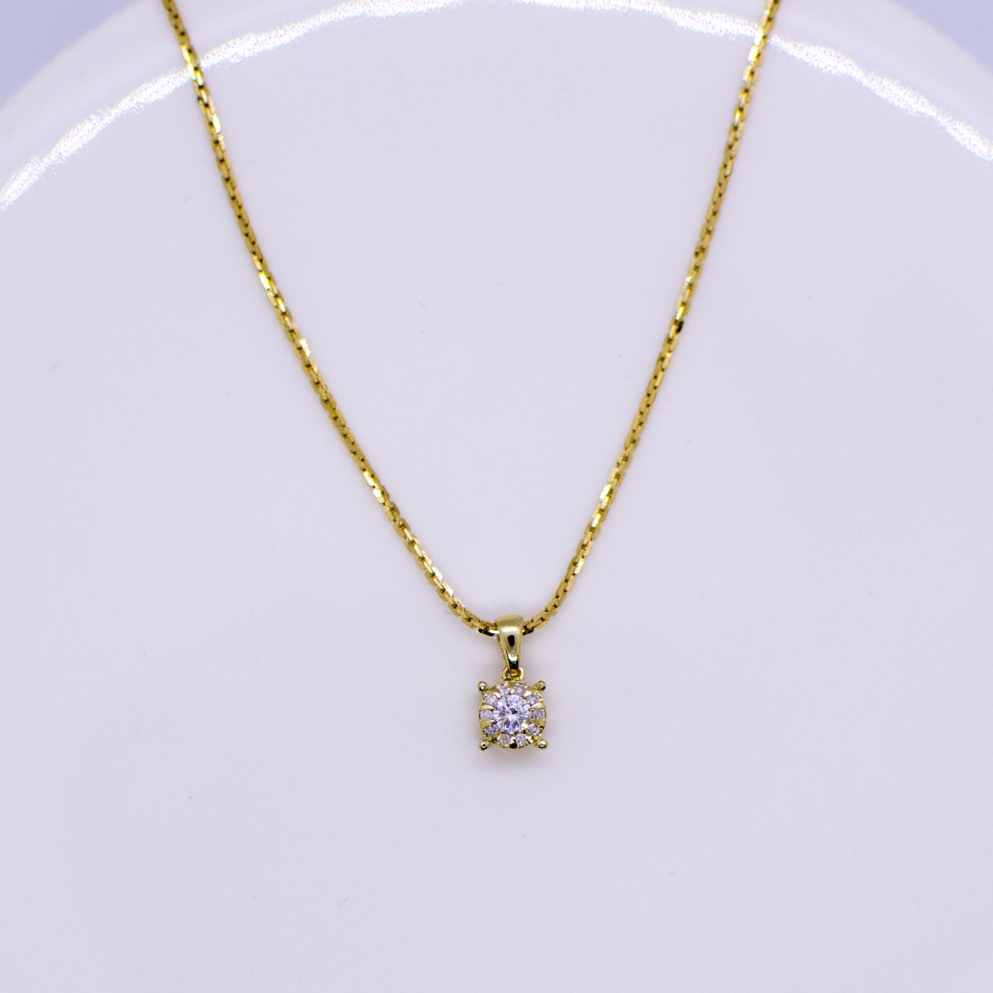 An illusion set round shaped pendant set with eleven round brilliant cut diamonds  9ct yellow gold 18" long 9ct yellow gold tight linked diamond cut square trace chain with lobster clasp.