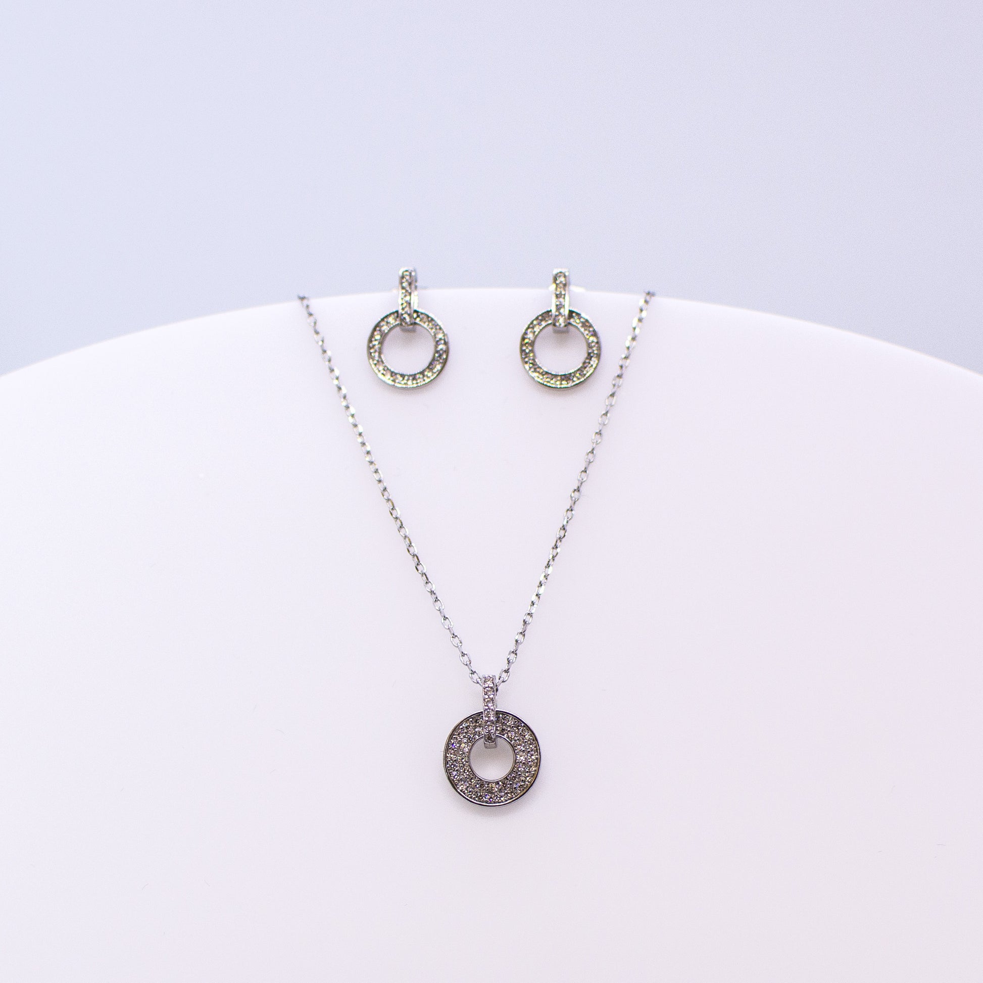 These sterling silver drop open circle stud earrings set with glittering cubic zirconia stones accompanied by the matching necklace are the perfect addition to any outfit. Product details: Product materials: 925 sterling silver, cubic zirconia Pendant dimensions:  13.5mm L x 10mm W Chain length: 44cm inch fine diamond cut curb chain Earring dimensions:  13mm L x 8.5mm W Stud earrings with butterfly backs.