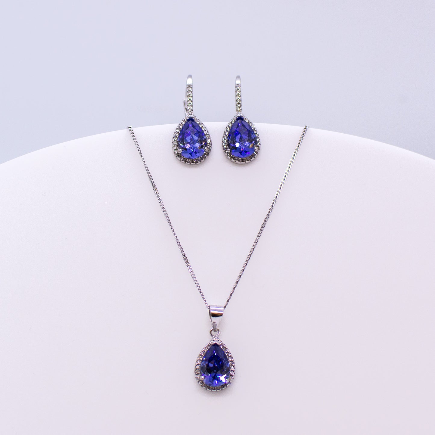 These sterling silver pear shaped drop earrings set with glittering cubic zirconia stones in created Tanzanite and white accompanied by the matching necklace are the perfect addition to any outfit. Product details: Product materials: 925 sterling silver, cubic zirconia Chain length: 44cm inch fine diamond cut curb chain Pendant dimensions:  20mm L x 10mm W Earring dimensions:  24mm L x 10mm W Drop earrings with integrated CZ set German wires.