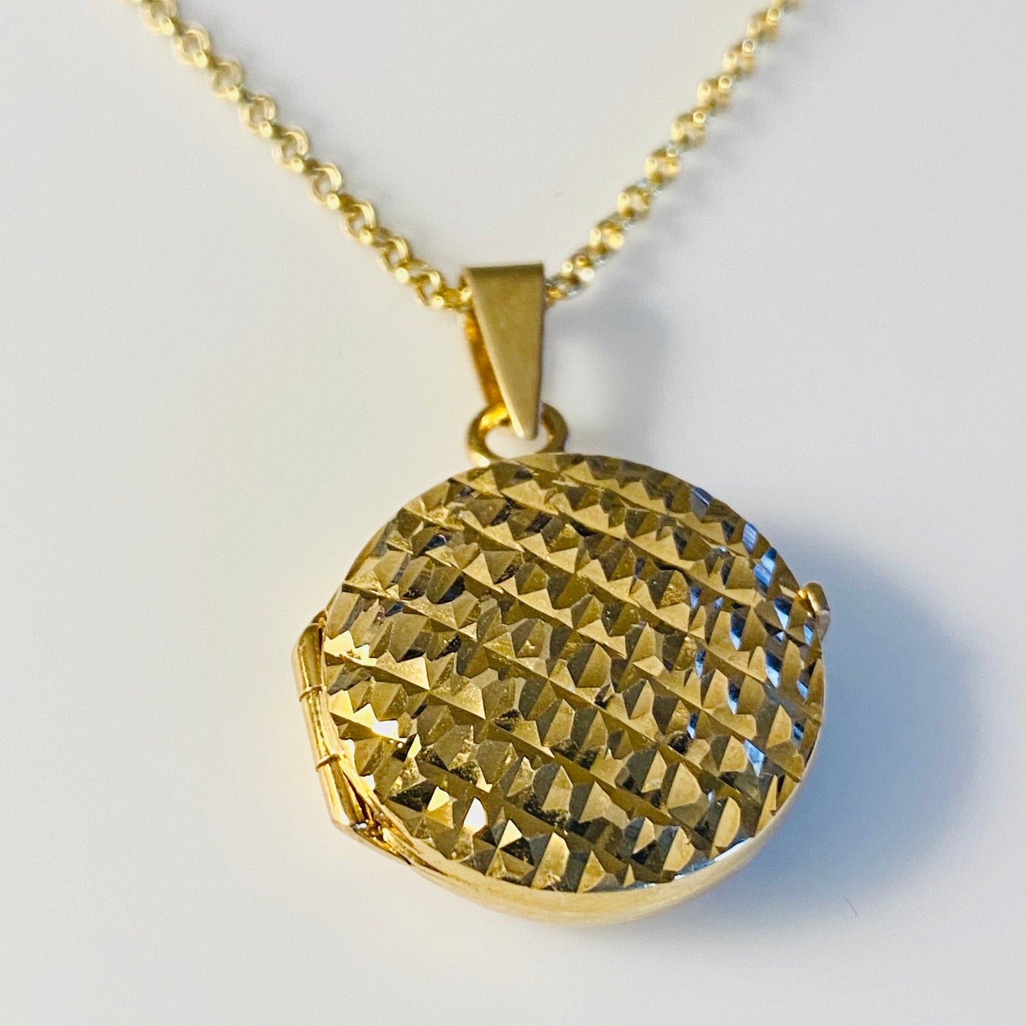 This 925 silver yellow gold plated round locket holds two photos.  It has a polished finish on the back and an intricate diamond cut pattern on the front.  It can be engraved on the back.  It hangs from a 925 silver yellow gold plated  46cm mini belcher chain.  This is so classic and stylish.  A completely "wear anytime" piece. Engraving is free of charge.