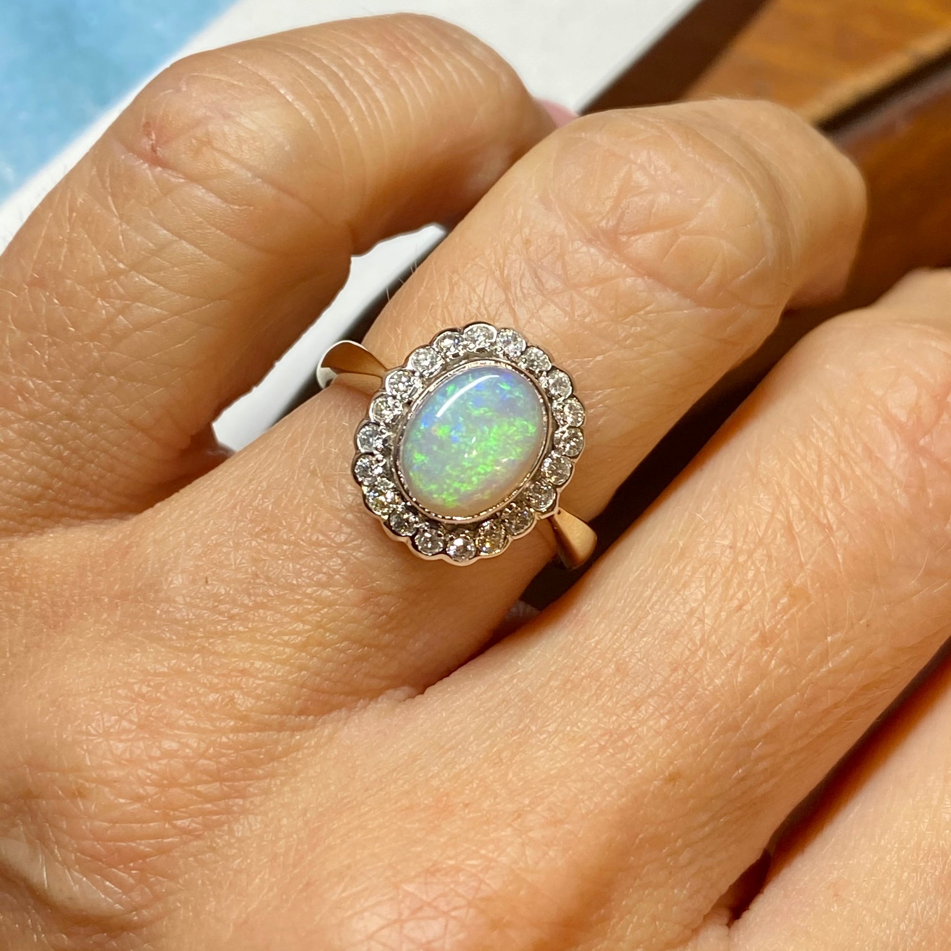 9ct Gold Opal & Diamond Ring  An oval cut gem opal is surrounded by a halo of diamonds with pretty vintage details in white gold.  The band is yellow gold.  9ct yellow gold hallmarked  Dimensions of the setting: 14.5mm x 12mm  This is in stock and ready to ship immediately from our shop in Tralee, Co Kerry, Ireland.  Other sizes from K-T available to order, usually a three week delivery.  Just message us if you need a different size or you would like to pay in instalments.