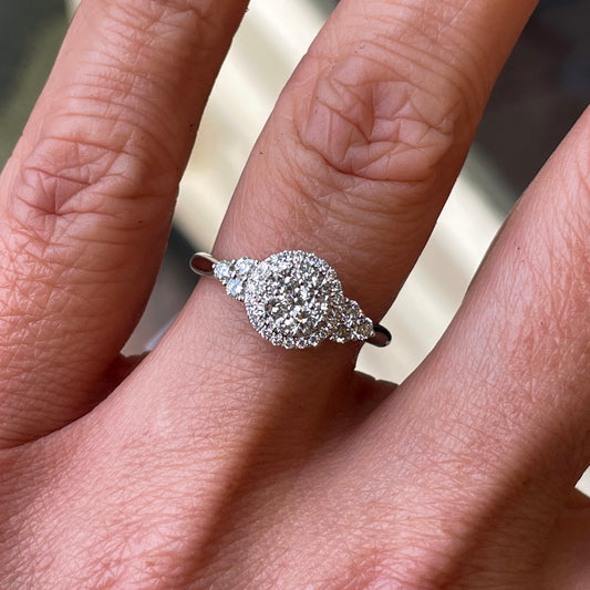 This round cluster diamond engagement ring  is a complete classic.  Its simplicity is so romantic.  The Details...  One 18ct white gold diamond engagement ring.  Diamond halo cluster in a round shape with trio shoulders. 0.65ct in total of diamonds.  Colour G.  Clarity VS.  18ct white gold.  Size N.