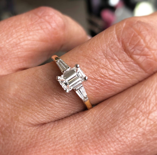 18ct Gold Emerald Cut Solitaire Engagement Ring | 0.94ct  Emerald Cut Diamond 0.71ct HSI  Tapered Baguette Shoulder Diamonds 0.23ct in total approximately HSI  18ct white gold setting, 18ct yellow gold band.