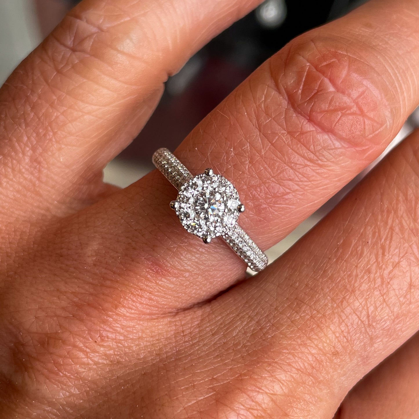 This round cluster diamond engagement ring  is a complete classic.  Its simplicity is so romantic.  The Details...  One 18ct white gold diamond engagement ring.  Diamond halo cluster in a round shape with pavé diamond-set shoulders. 0.74ct in total of diamonds.  Colour G.  Clarity VS.  Centre stone: 0.26ct  Melée: 0.48ct  18ct white gold.  Size N