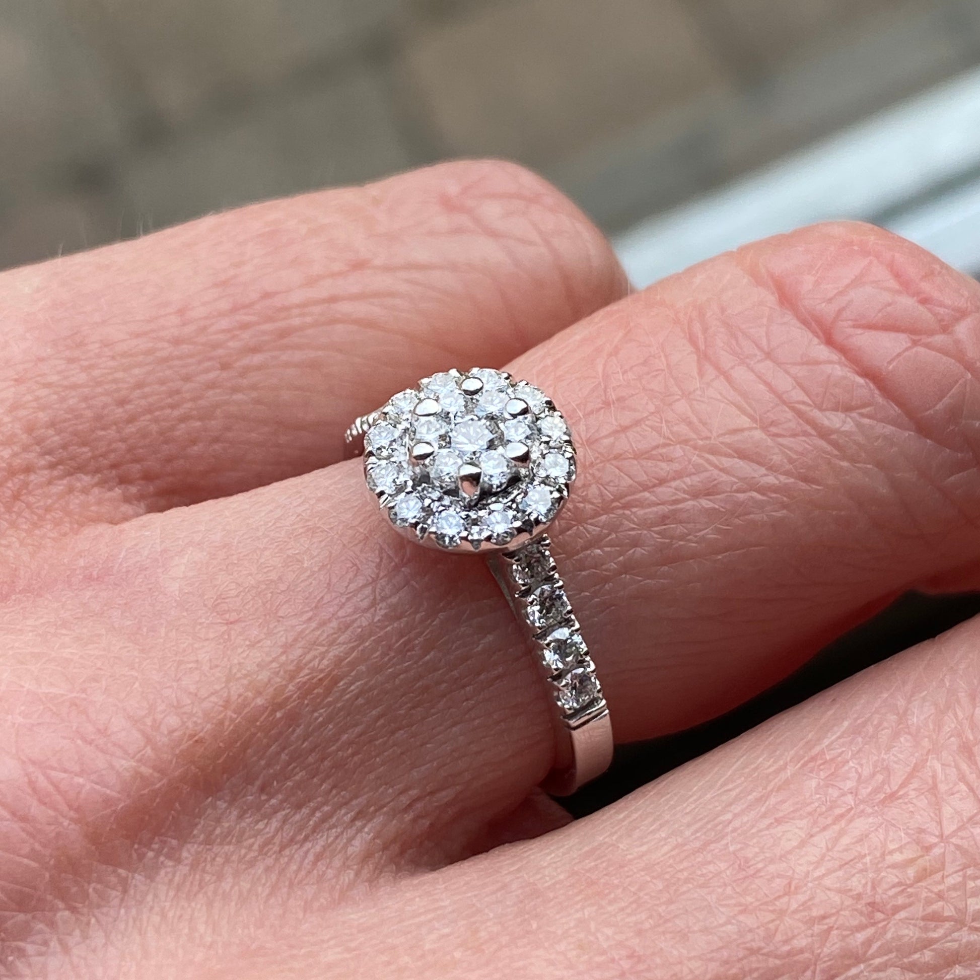 This round cluster diamond engagement ring  is a complete classic.  Its simplicity is so romantic. The Details... One 18ct white gold diamond engagement ring.  Diamond halo cluster with diamond-set shoulders. 0.66ct in total of round brilliant cut diamonds.  Colour GH.  Clarity SI. 18ct white gold, Pure White (tm) nickel-free.  Size N.