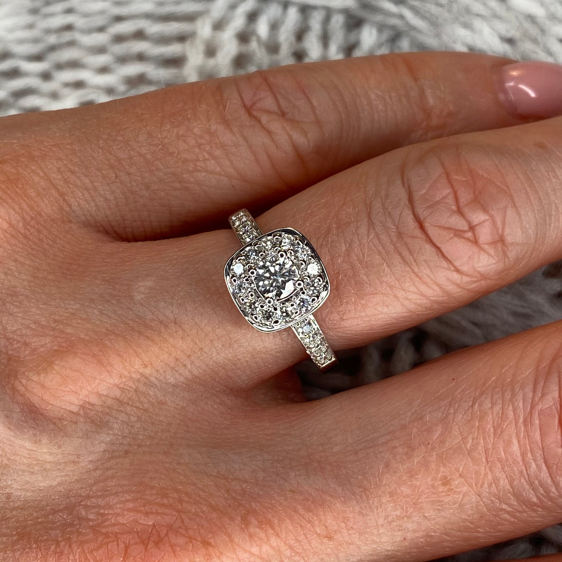 9ct White Gold Halo Diamond Engagement Ring 0.75ct in total approximately. A round brilliant cut diamond set in four claws with a cushion shaped halo of round brilliant cut diamonds and straight diamond set shoulders.